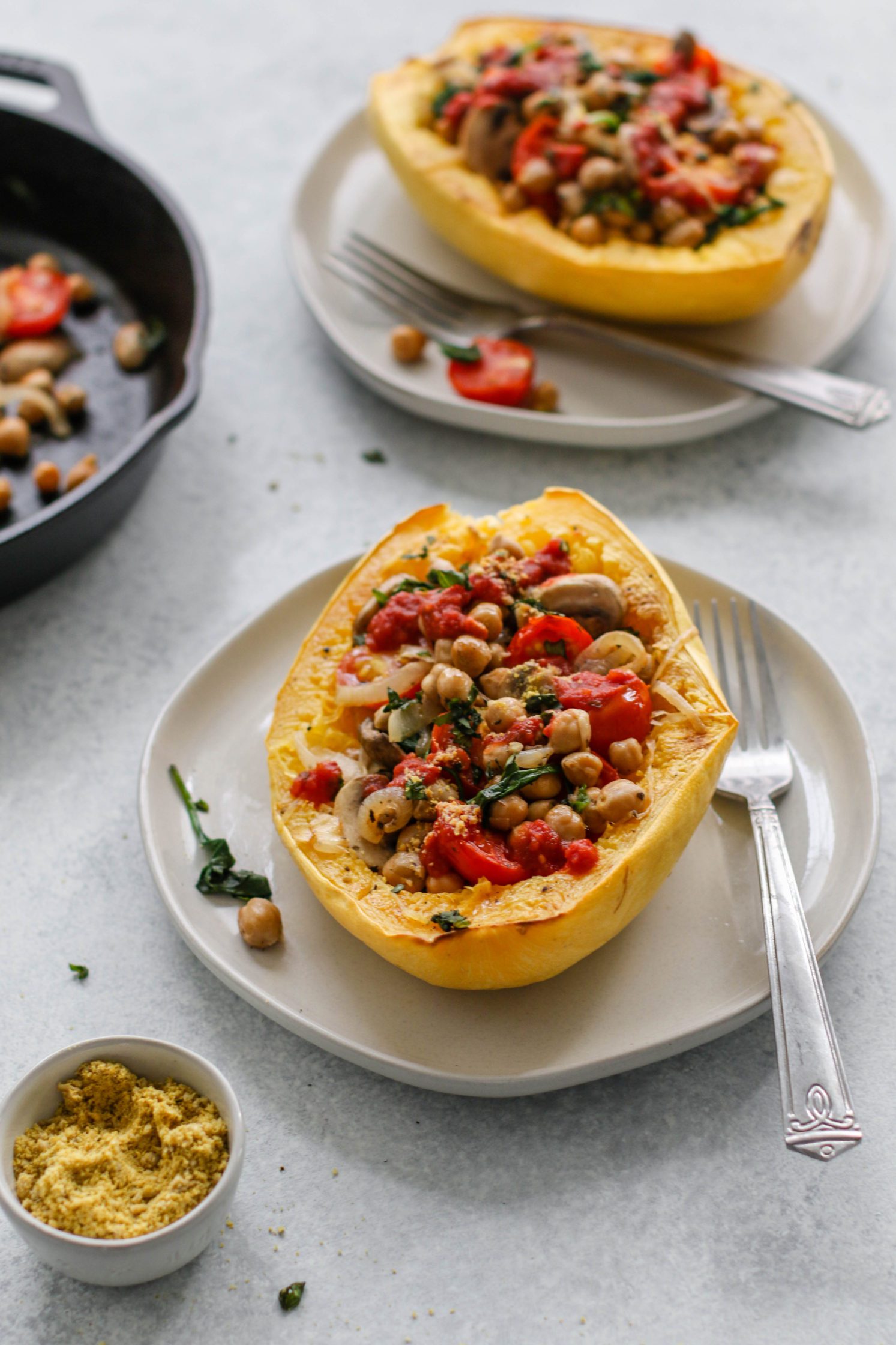Italian Stuffed Spaghetti Squash served on plates with forks with Crispy Chickpeas by Flora & Vino