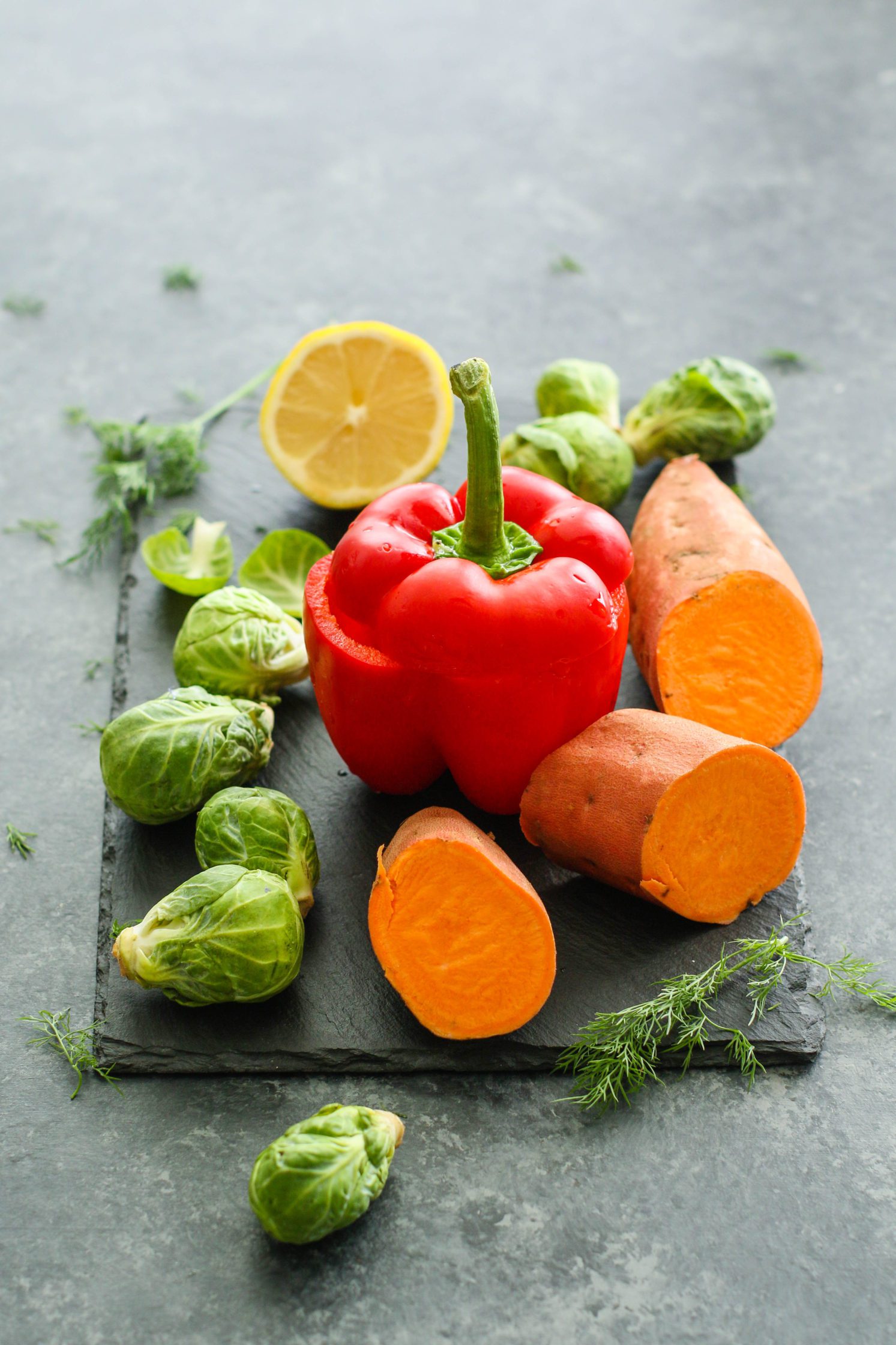 bell pepper, sweet potato, brussels sprouts, and lemon on a cutting board by Flora & Vino