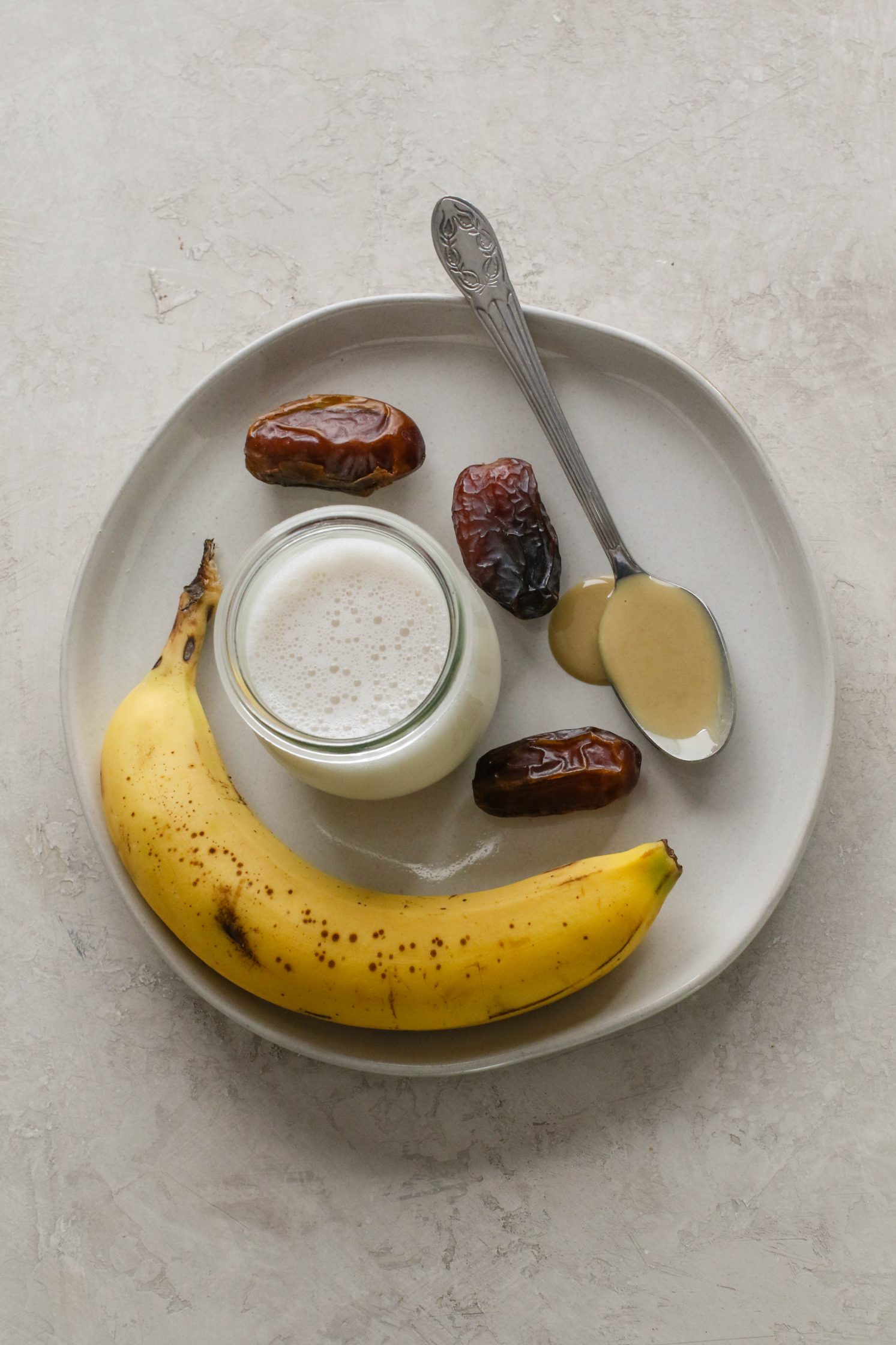 tahini, dates, banana, and milk on white plate by Flora & Vino