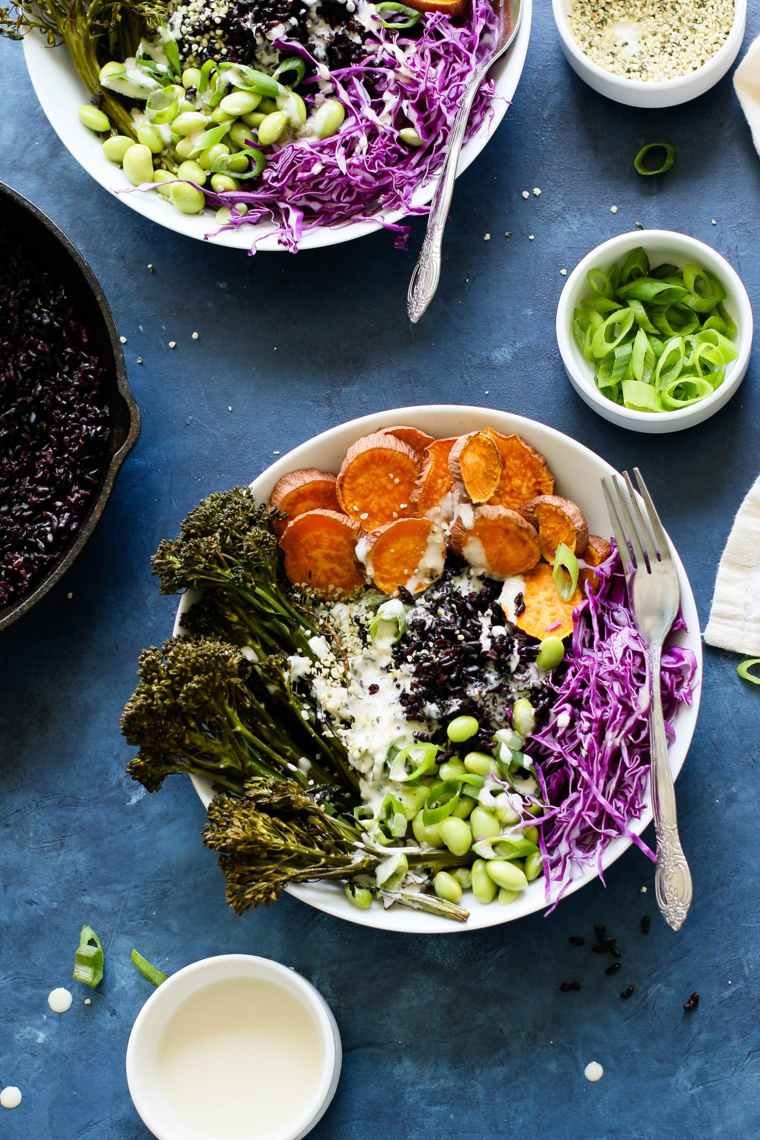 Sweet Potato & Forbidden Rice Power Bowls topped with miso tahini served in bowls with fork