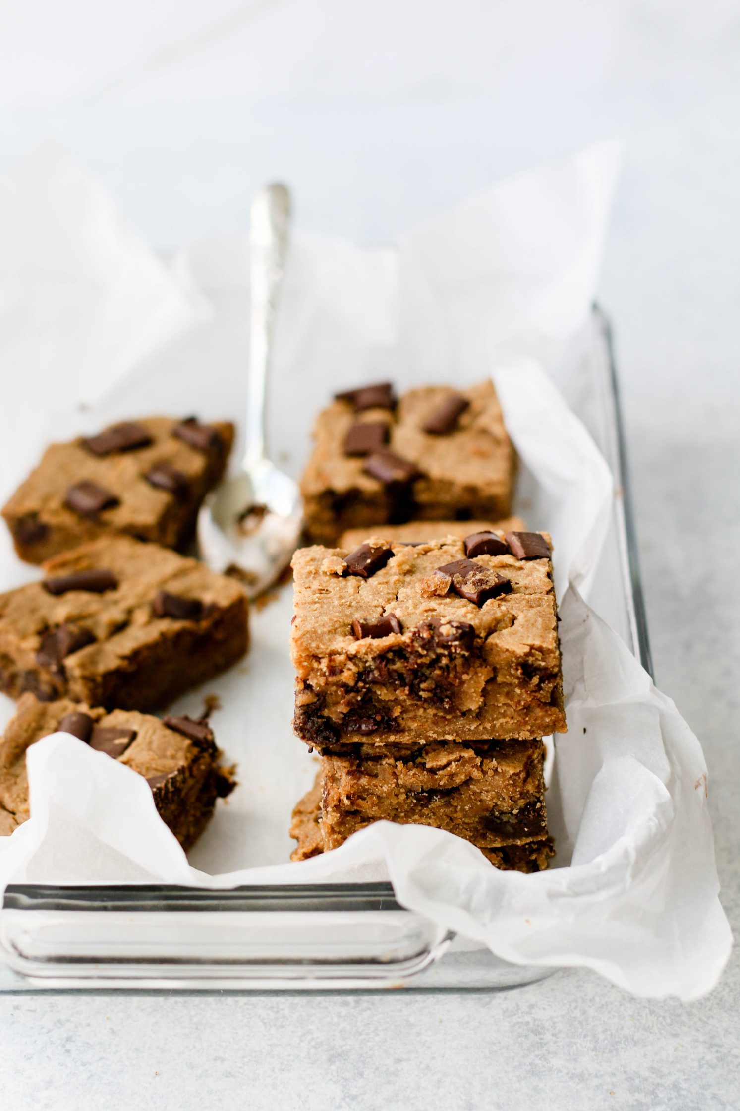 White Bean Blondies stacked in parchment lined baking dish by Flora & Vino