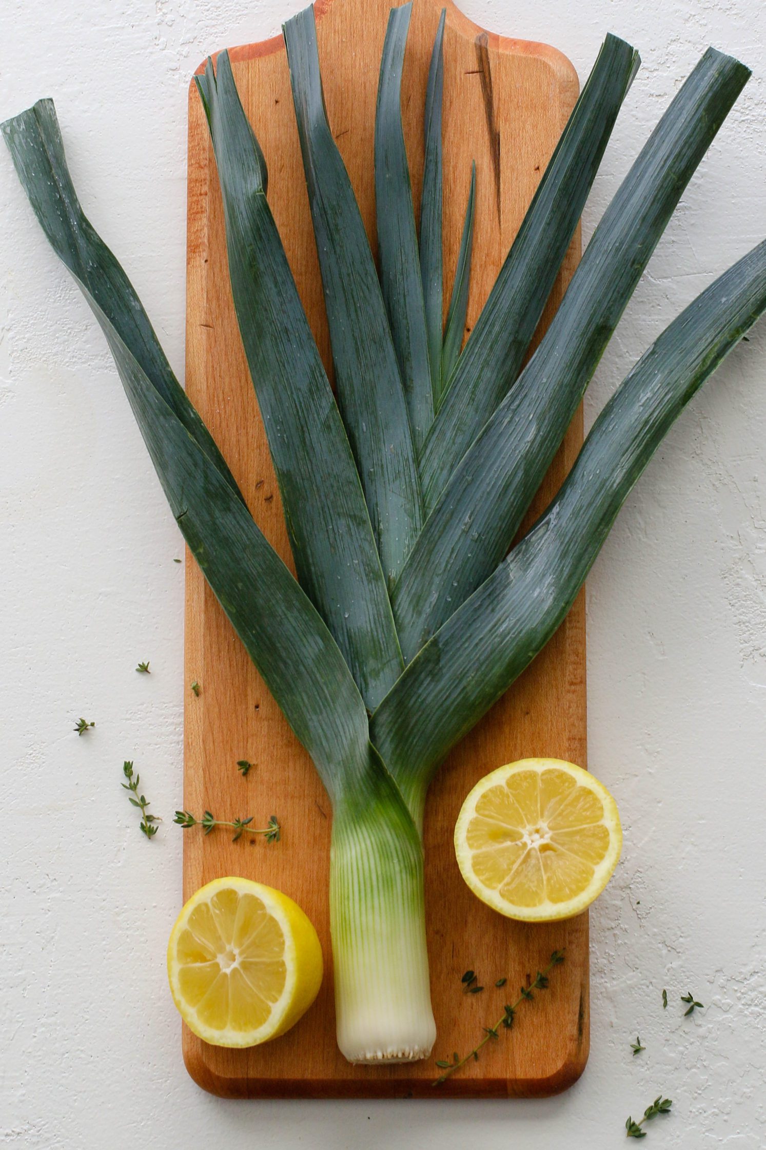fresh leek on wooden board with fresh thyme and halved lemon