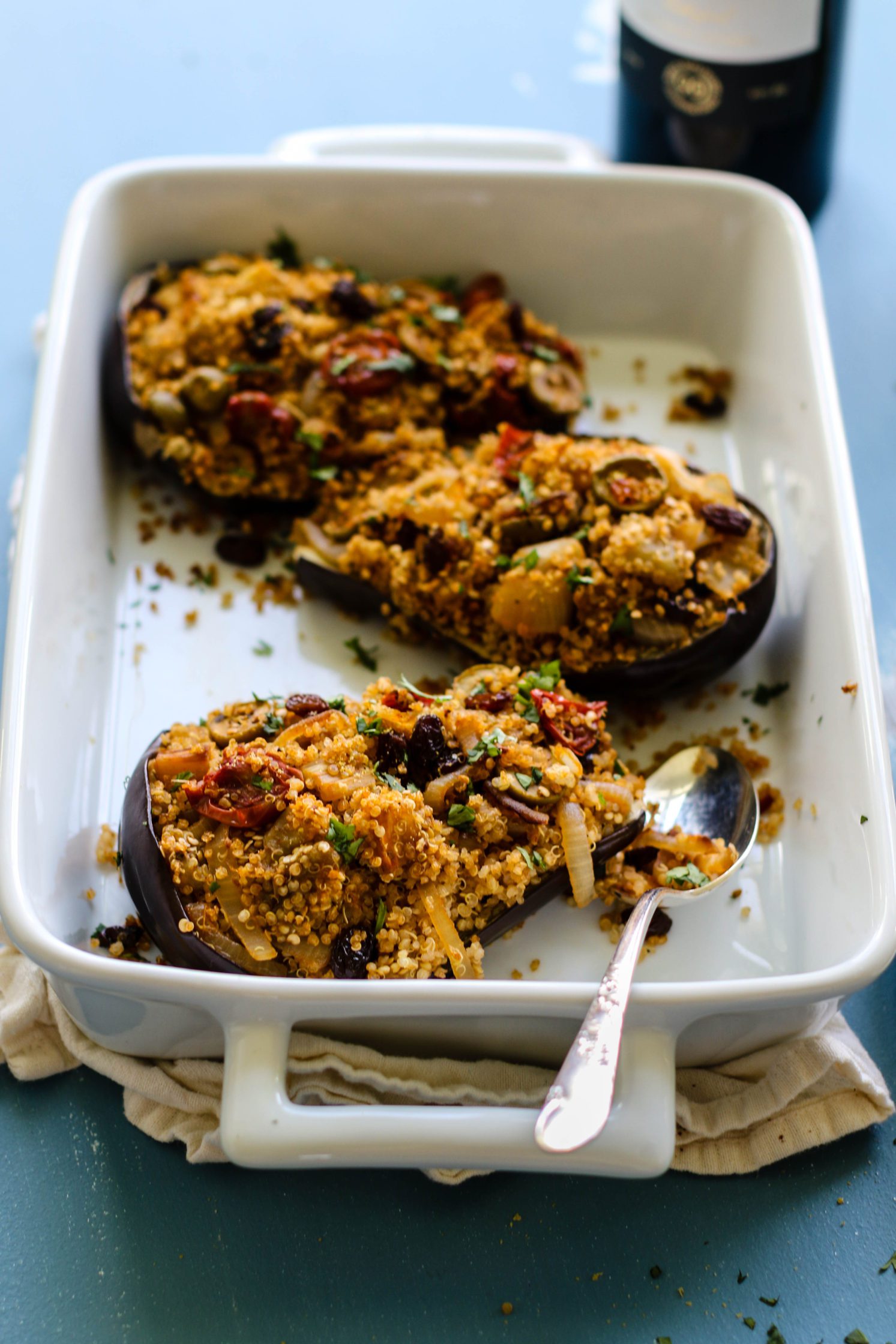 Quinoa Stuffed Eggplant in casserole dish with spoon by Flora & Vino