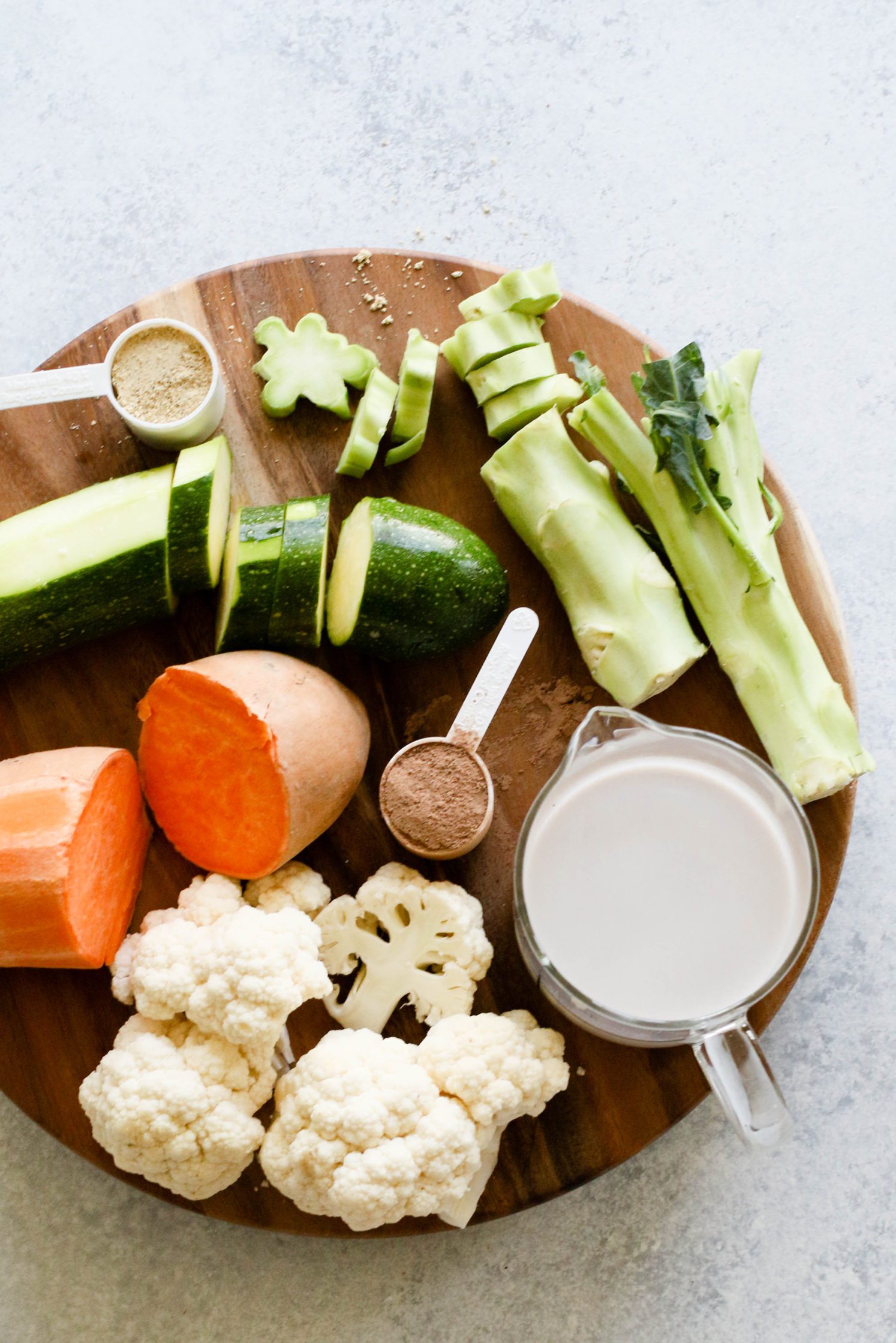 raw vegetables on wooden circle with almond milk by Flora & Vino