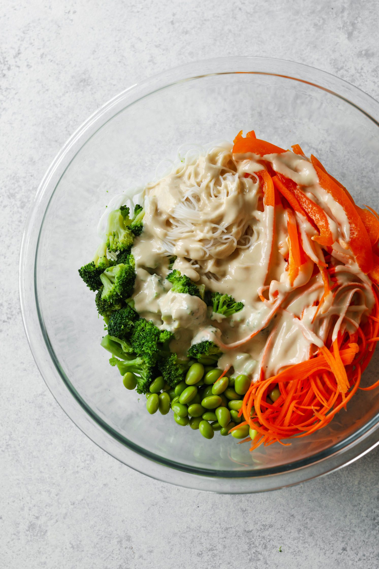 Rainbow Rice Noodle Bowls in glass bowl topped with miso tahini dressing 