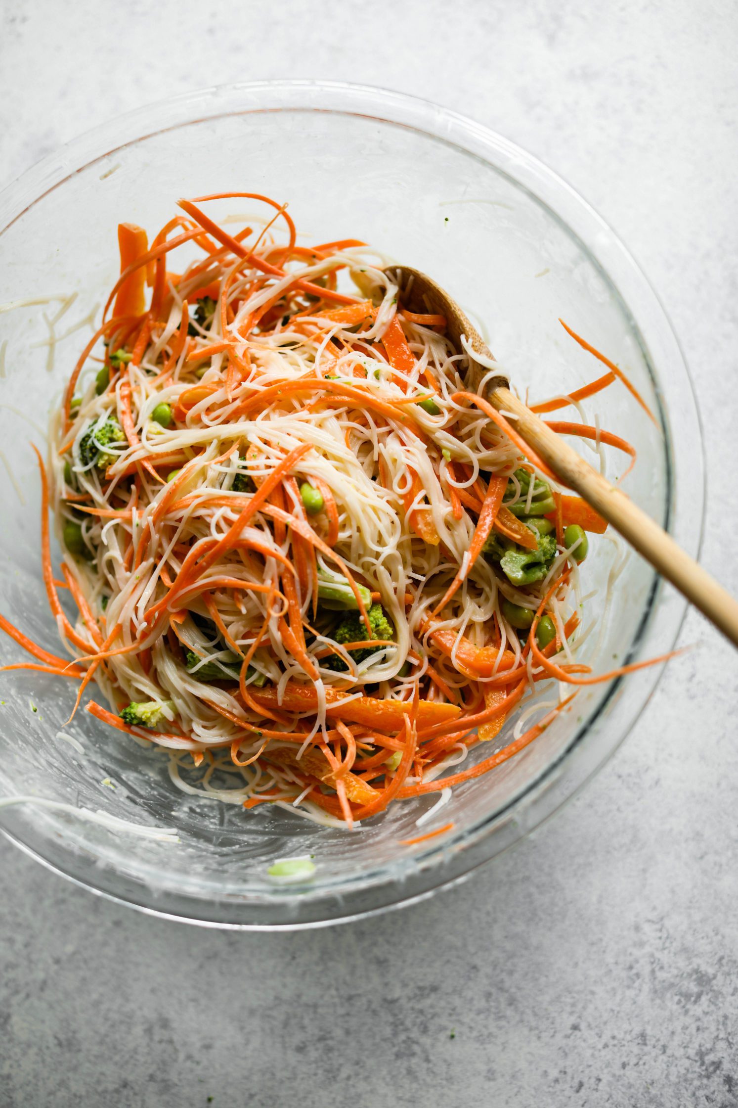 Rainbow Rice Noodles mixed in bowl with wooden spoon 