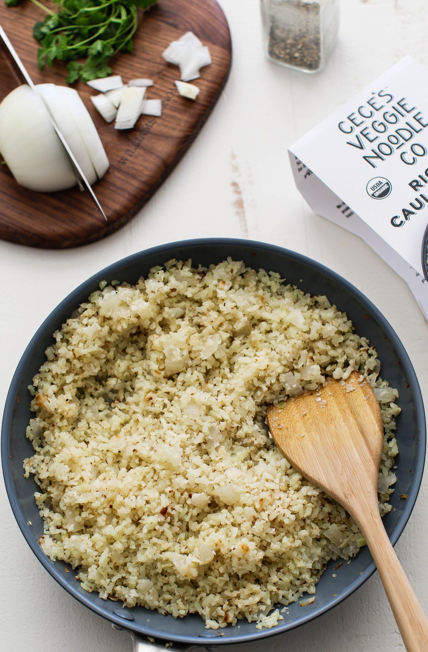 cauliflower rice cooked in pan with wooden stirrer
