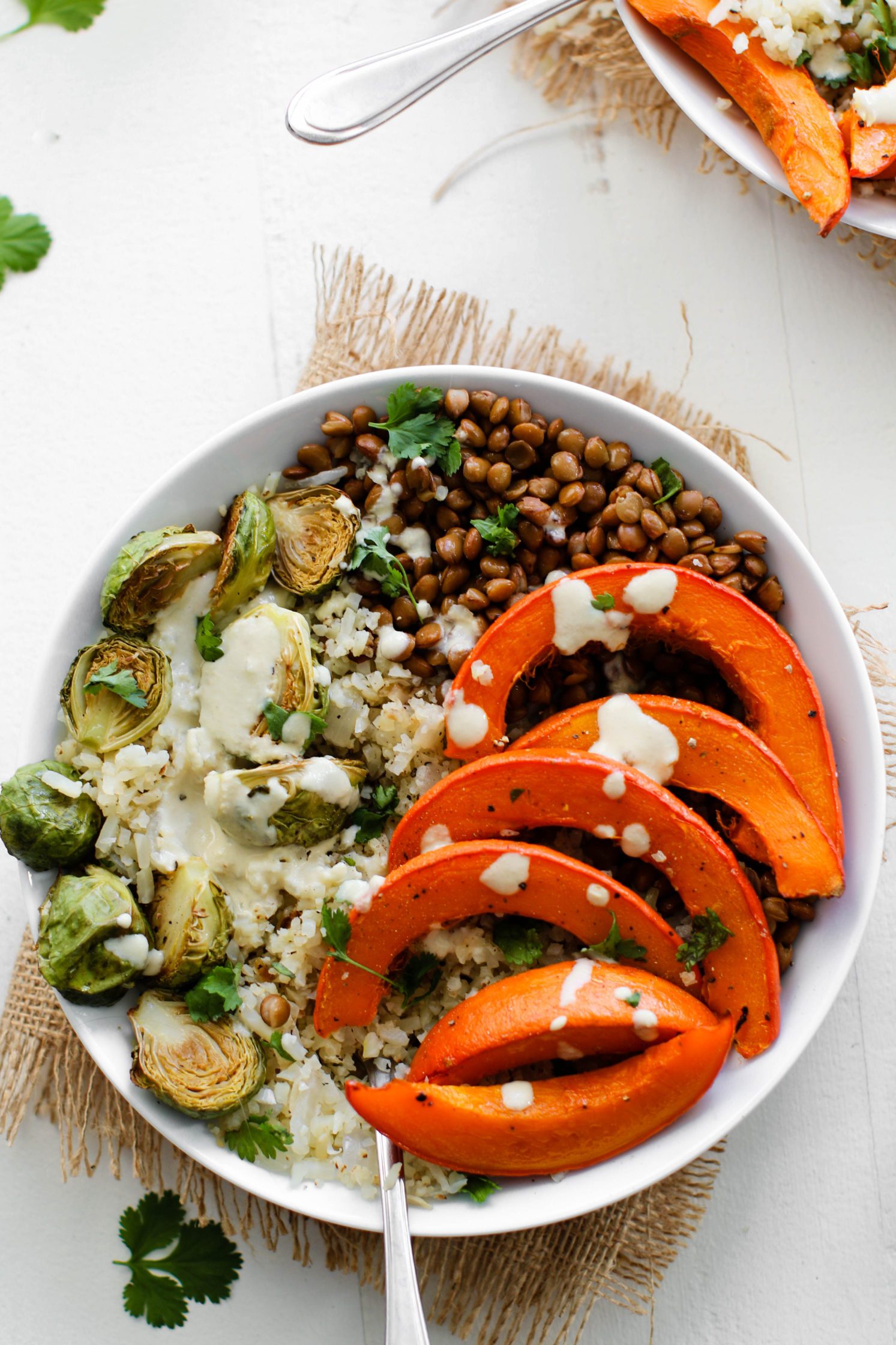 Lentil & Winter Squash Cauliflower Rice Power Bowl served in bowls topped with tahini dressing with spoons 