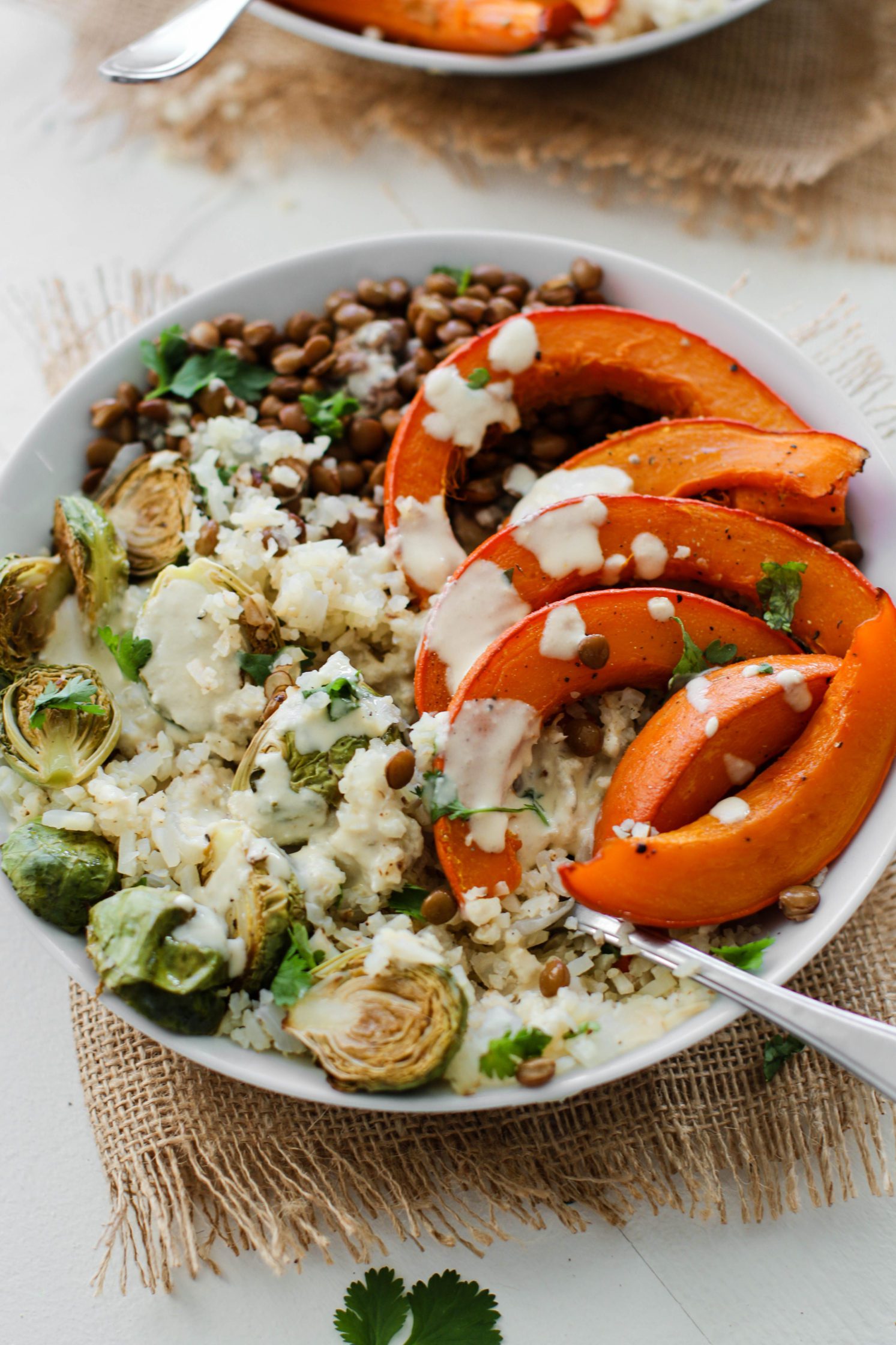 Lentil & Winter Squash Cauliflower Rice Power Bowl served in bowls topped with tahini dressing with spoons 