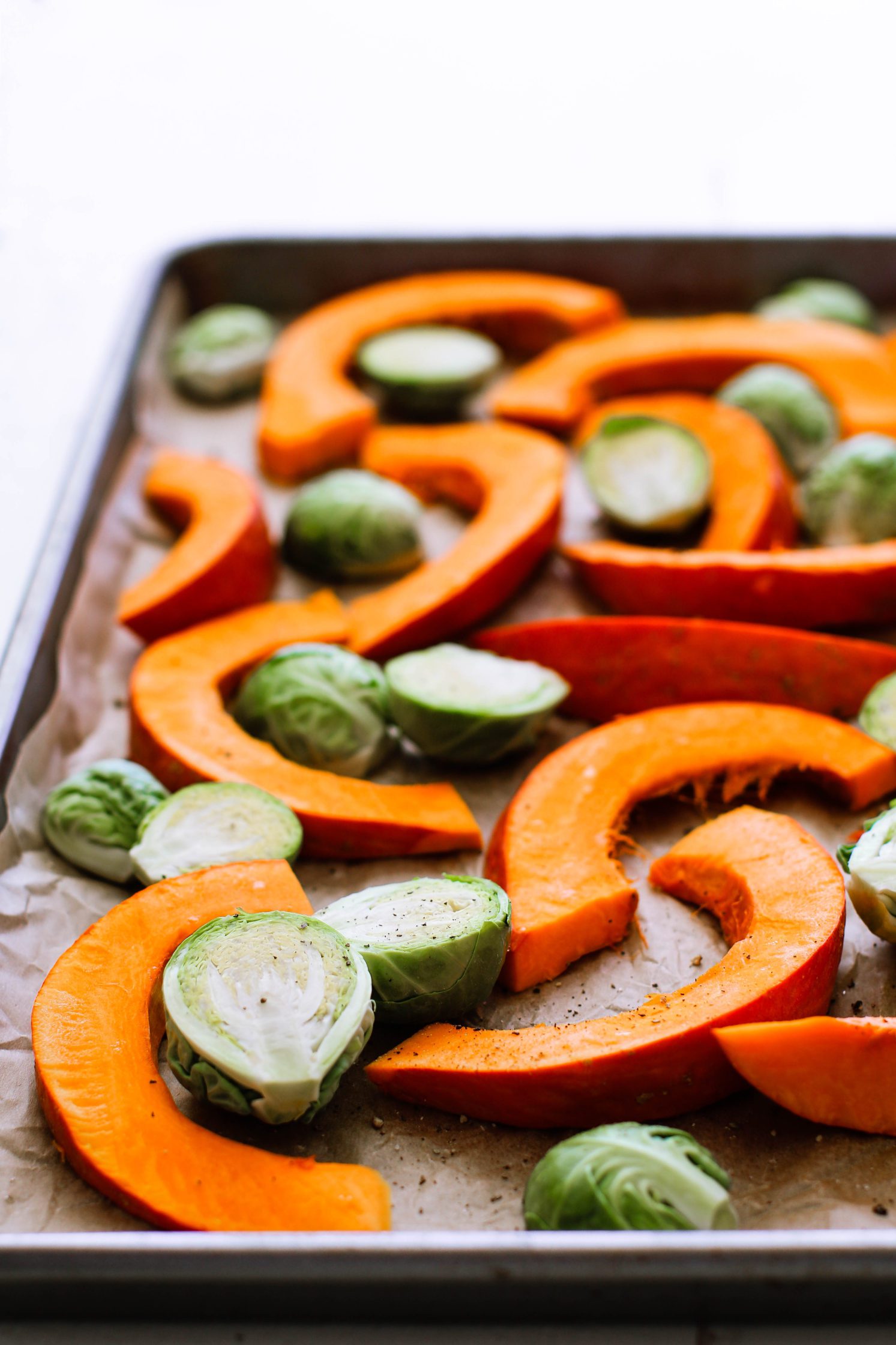 kuri squash and brussels sprouts on parchment lined baking sheet