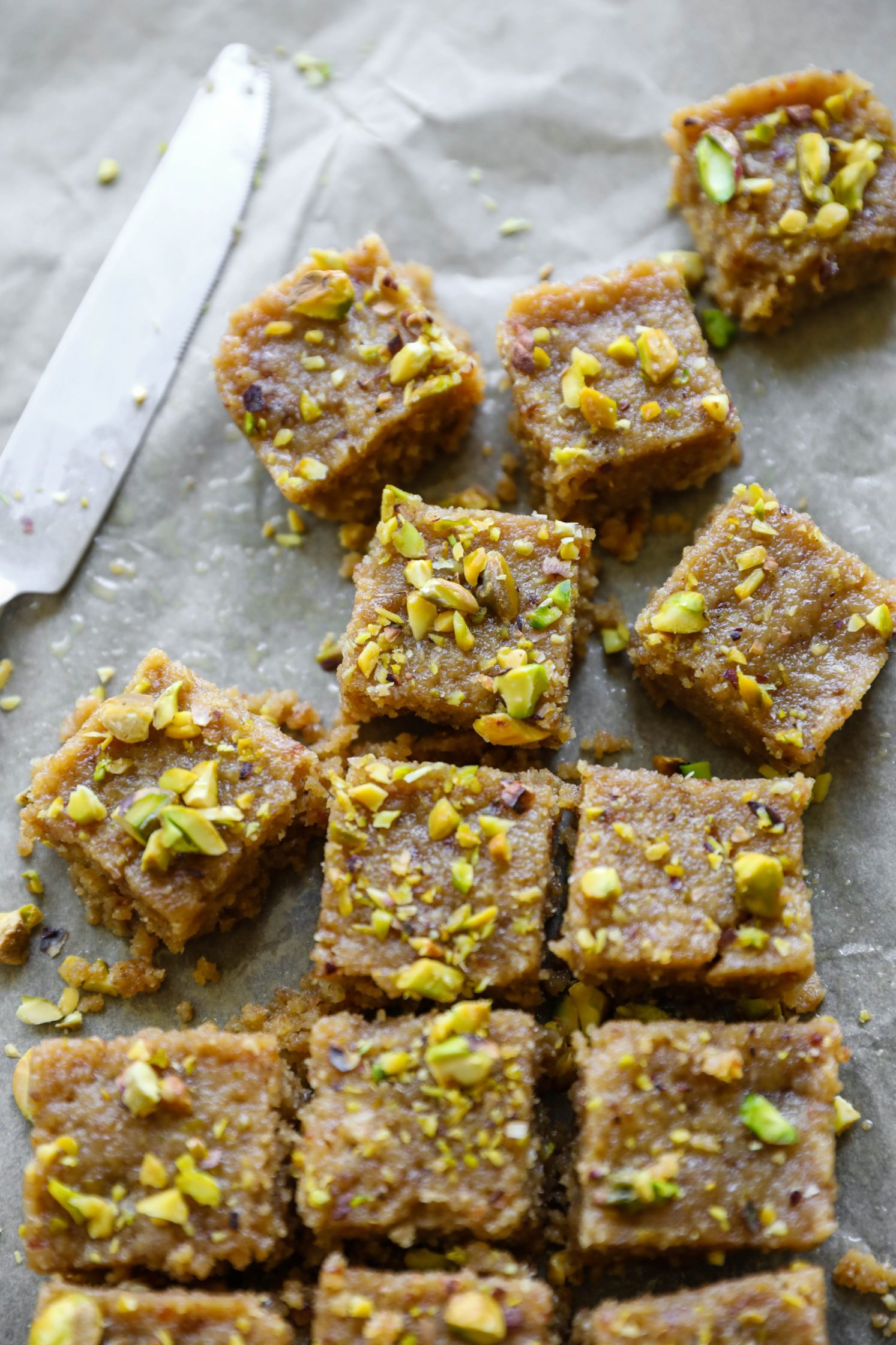 Vegan Tahini Date Halva cut on parchment paper with a knife by Flora & Vino