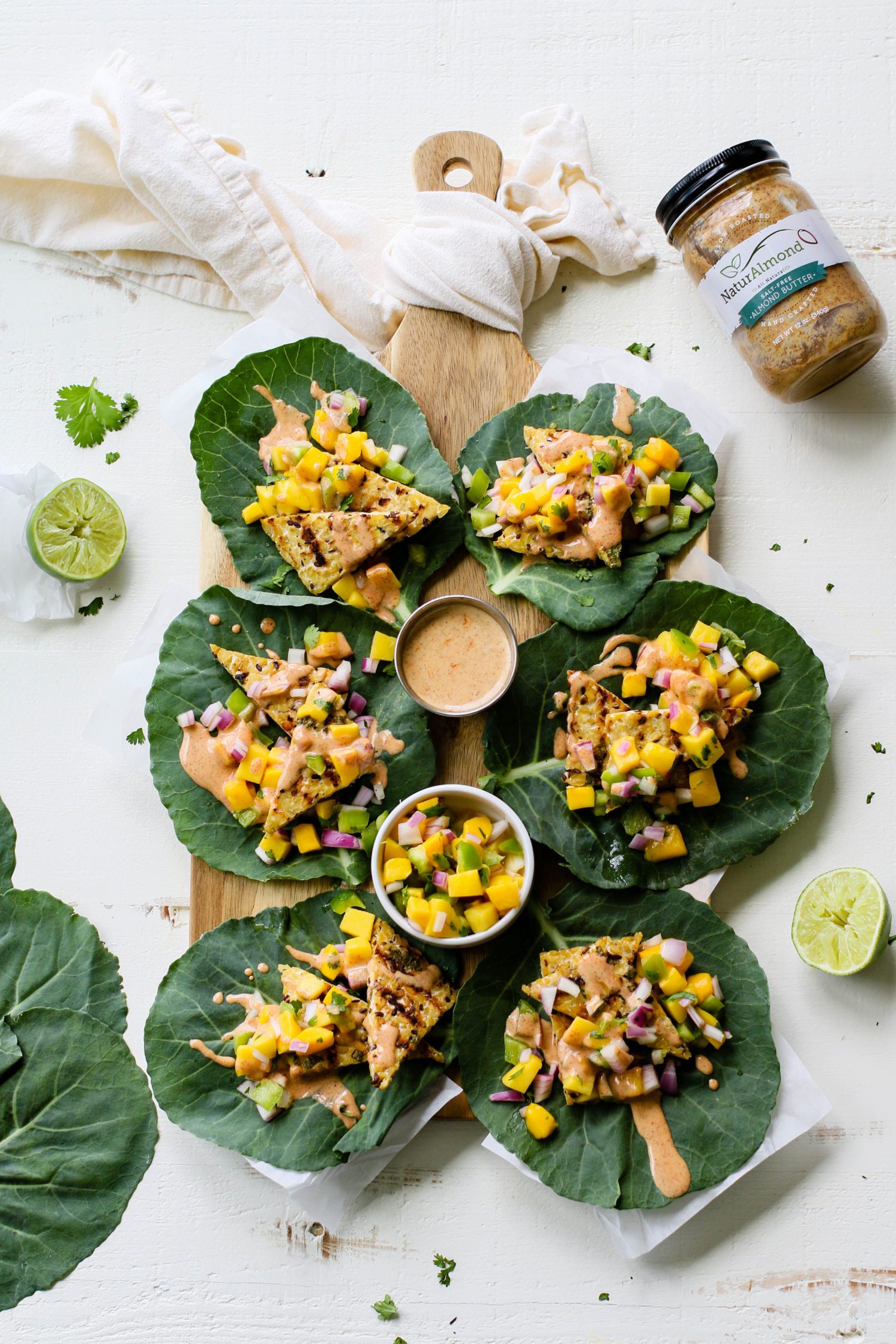 Grilled Tempeh Collard Wraps served on wooden board with Mango Salsa & Spicy Almond Butter Sauce