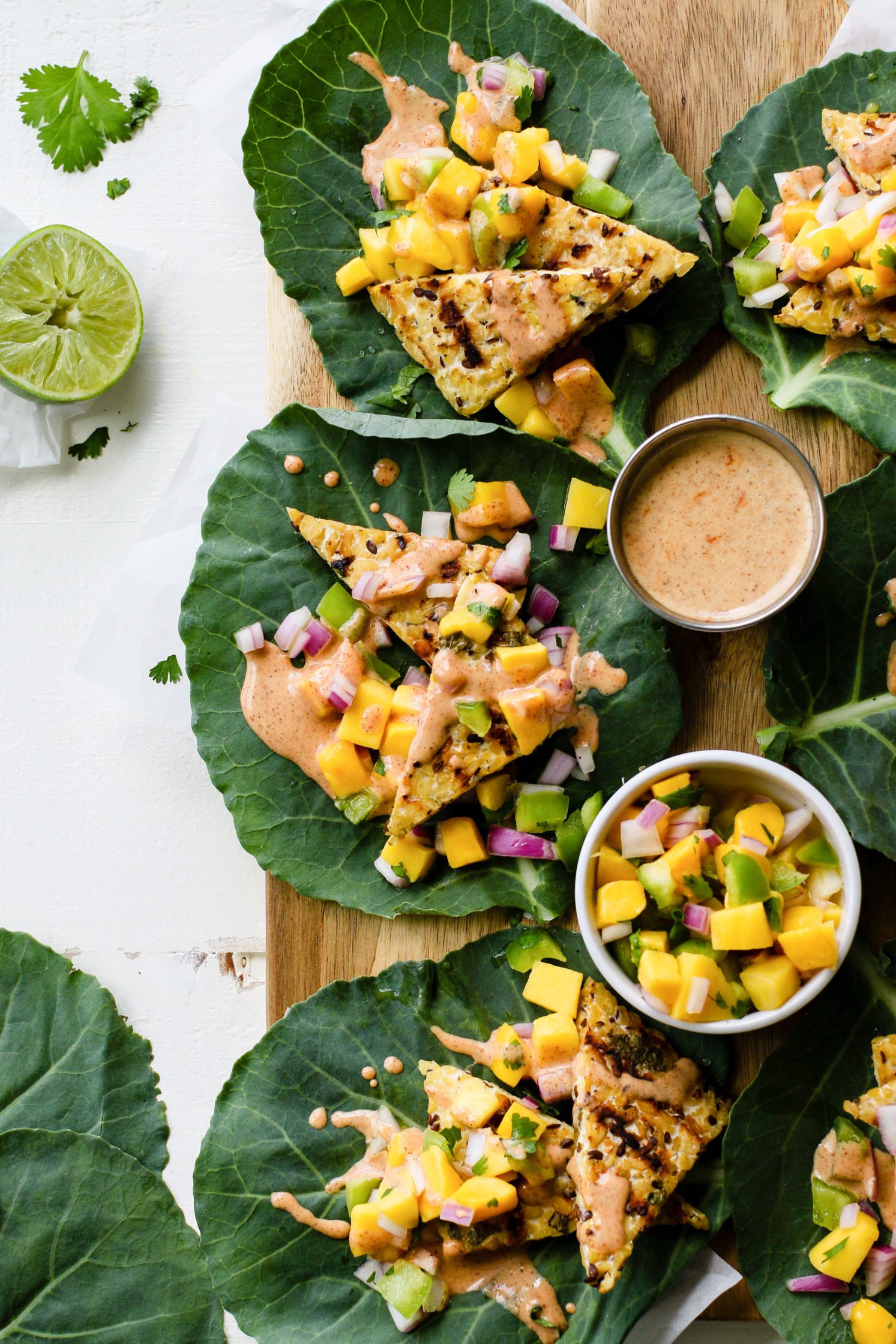 Grilled Tempeh Collard Wraps served on wooden board with Mango Salsa & Spicy Almond Butter Sauce