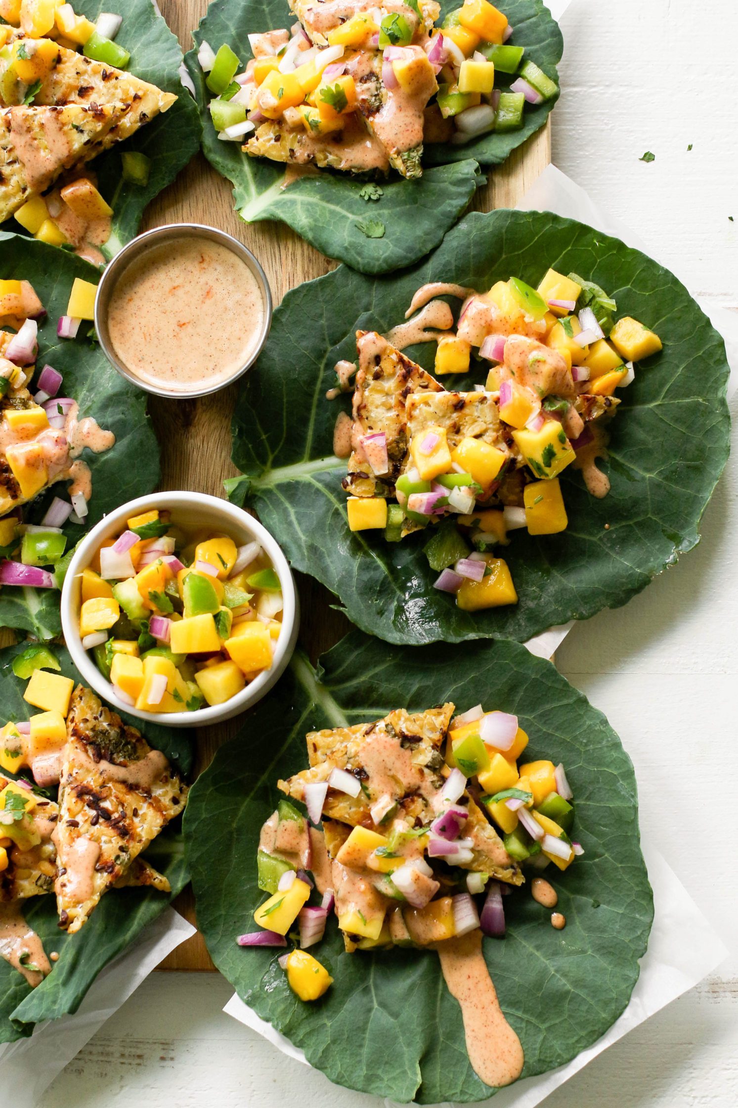 Grilled Tempeh Collard Wraps served on wooden board with Mango Salsa & Spicy Almond Butter Sauce
