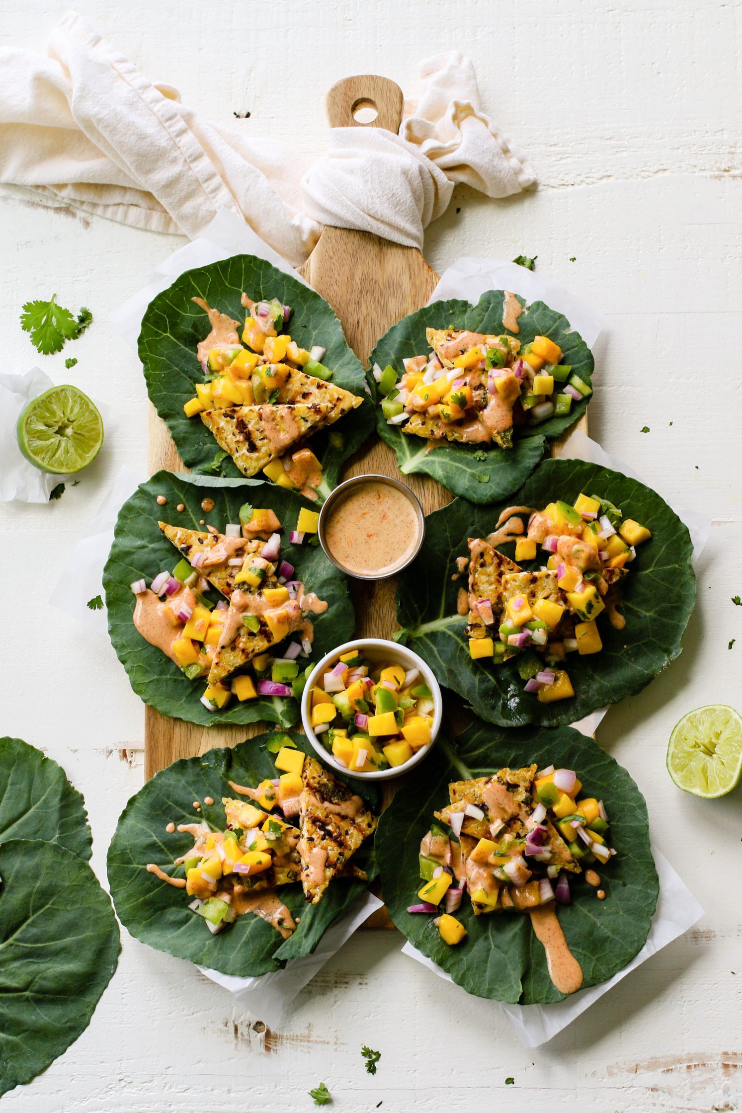Grilled Tempeh Collard Wraps served on wooden board with Mango Salsa & Spicy Almond Butter Sauce