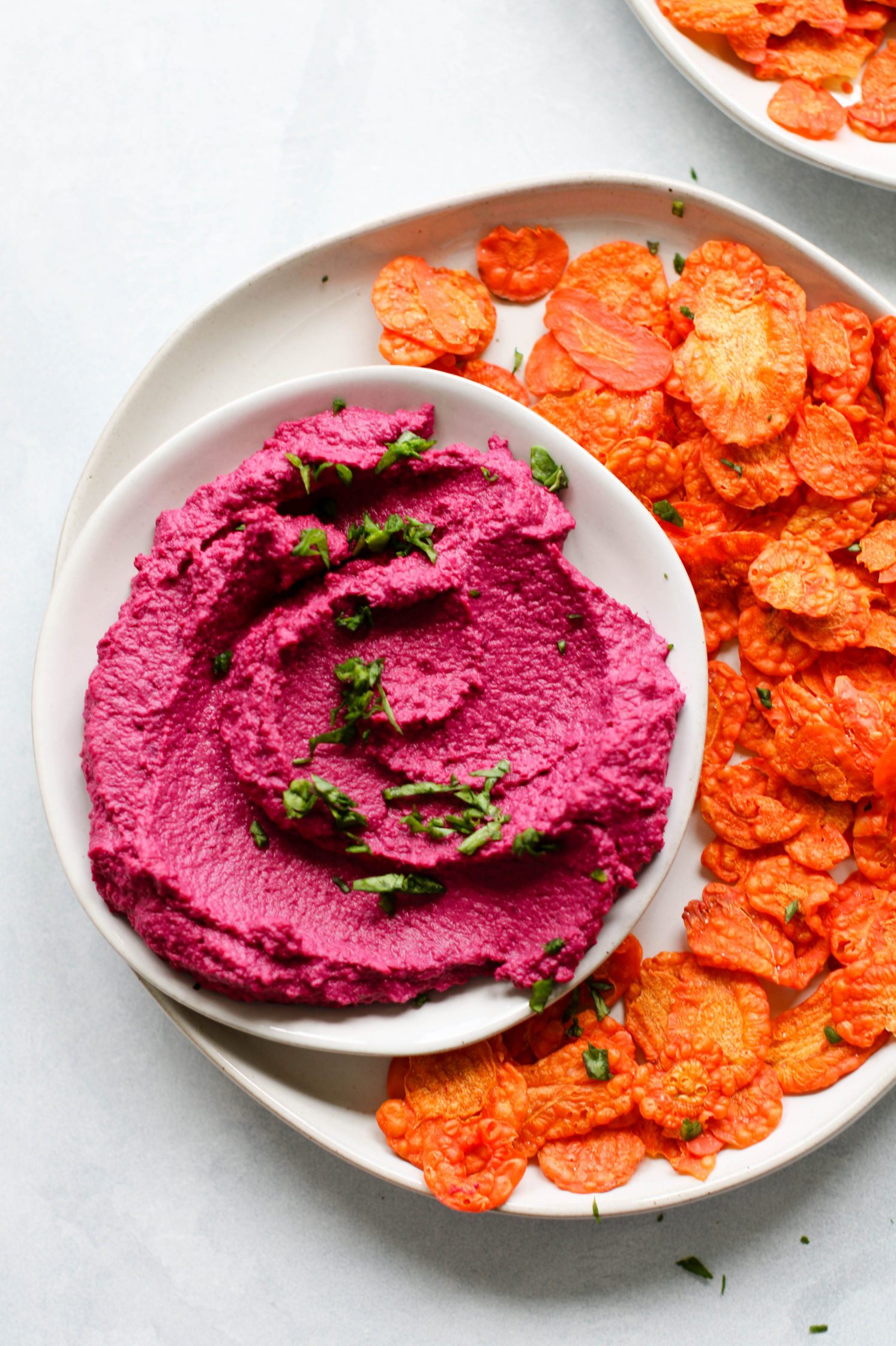 Easy Beet Hummus (Oil-Free!) served in a bowl with carrot chips by Flora & Vino