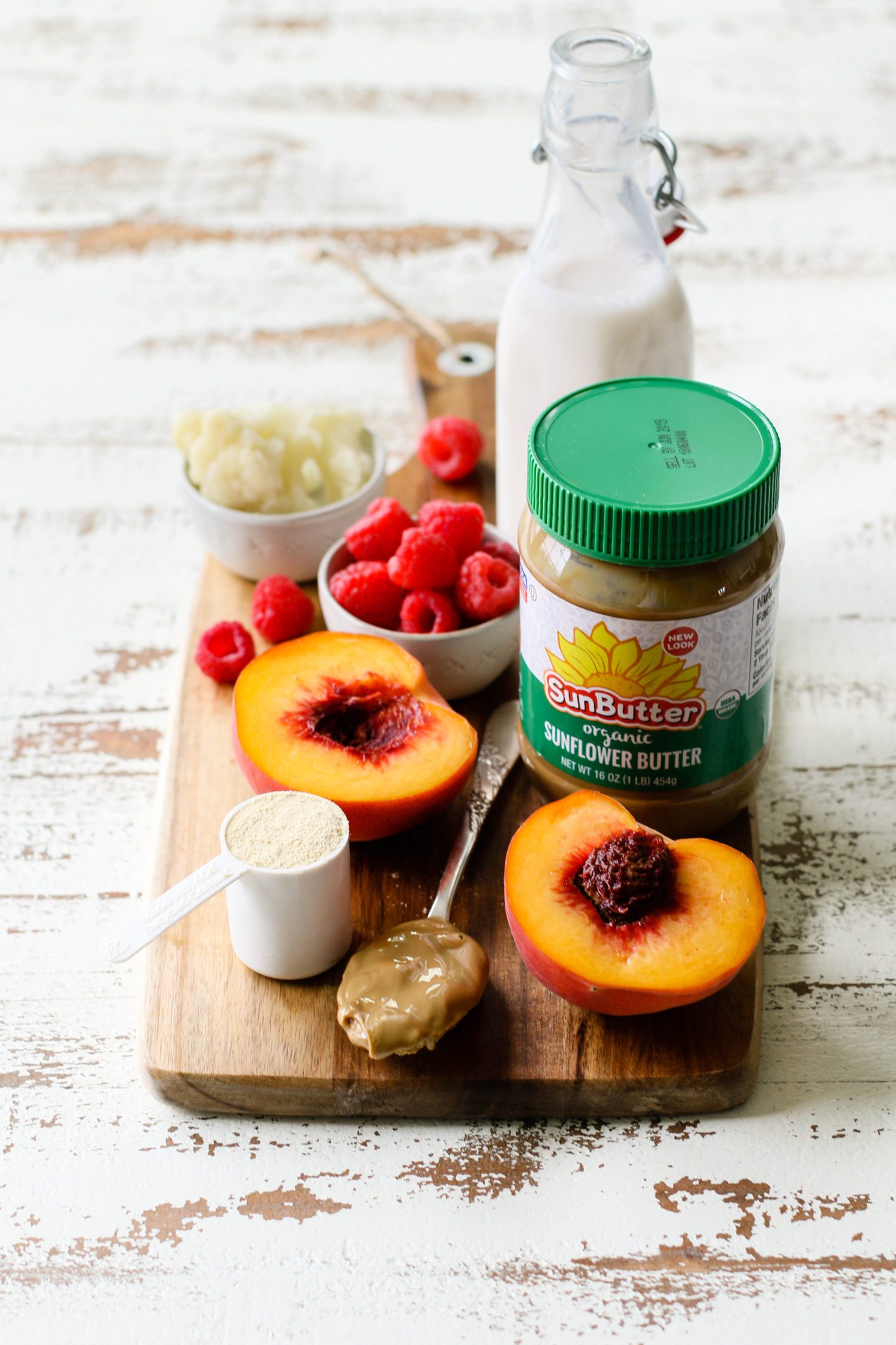 ingredients for Peach Raspberry Sunbutter Smoothie Bowl served on wooden board