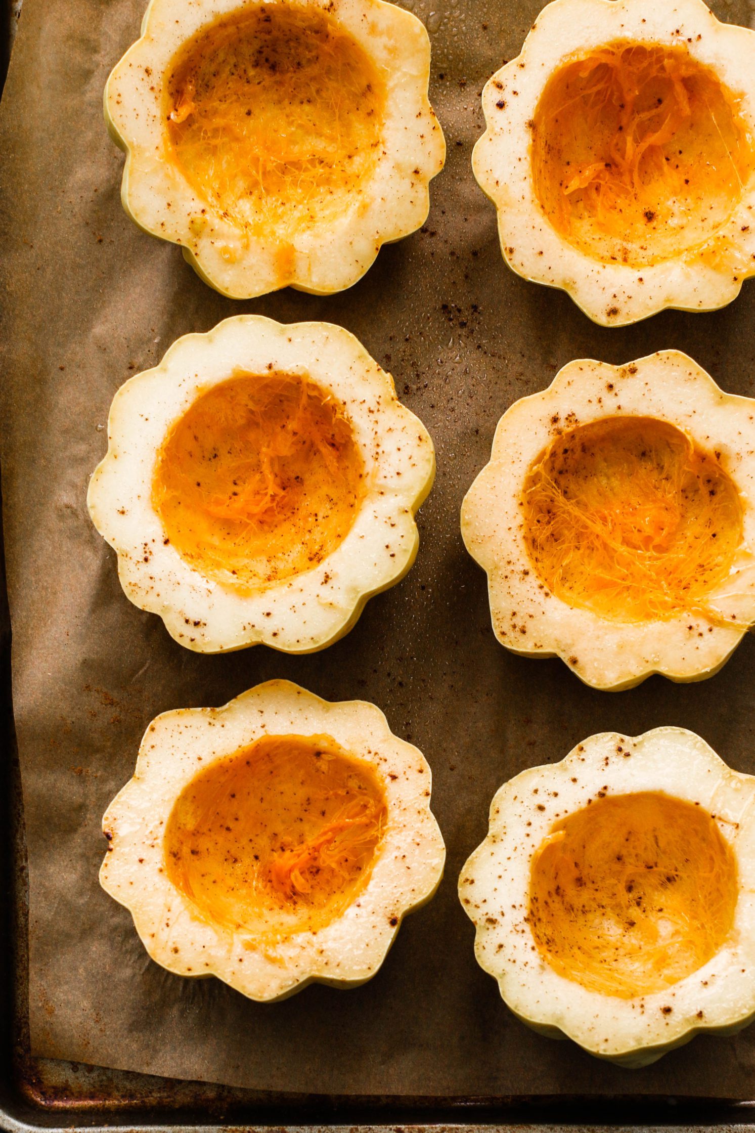 halved carnival squash on parchment lined baking sheet by Flora & Vino