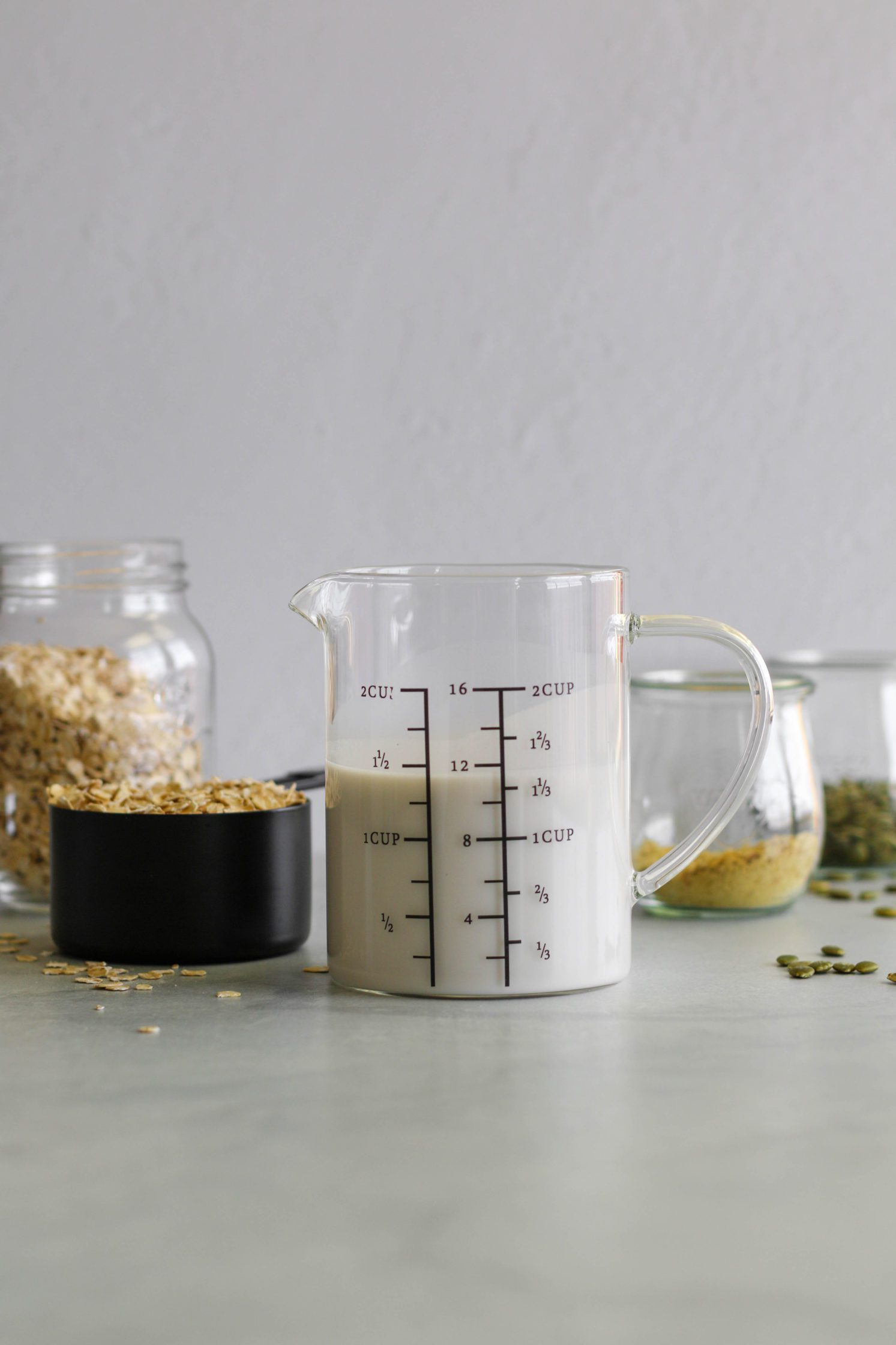 almond milk in pitcher with jar of oats, nutritional yeast, and pumpkin seeds
