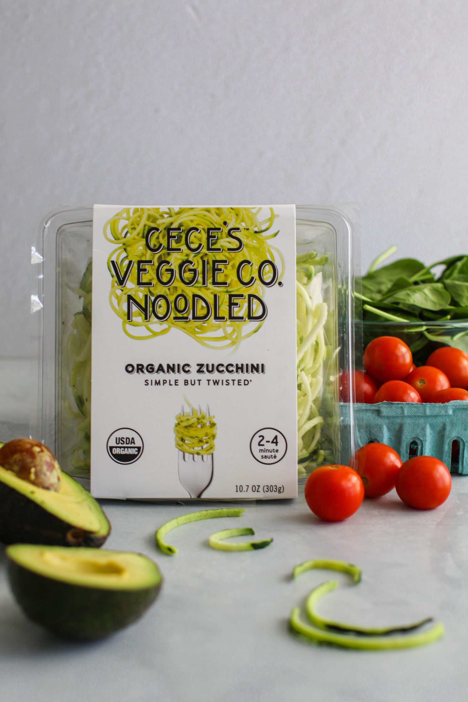 Cece's Veggie Co. Organic Zucchini Spirals in package with cherry tomatoes, spinach, and avocado around it