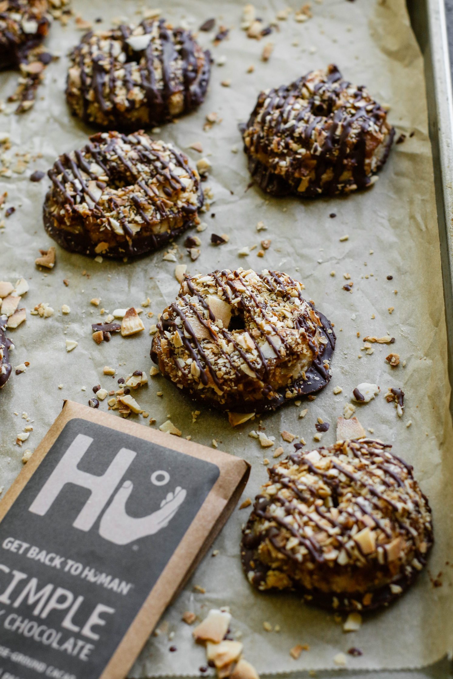 Vegan Toasted Coconut Samoas on parchment lined baking sheet with scattered toasted coconut 