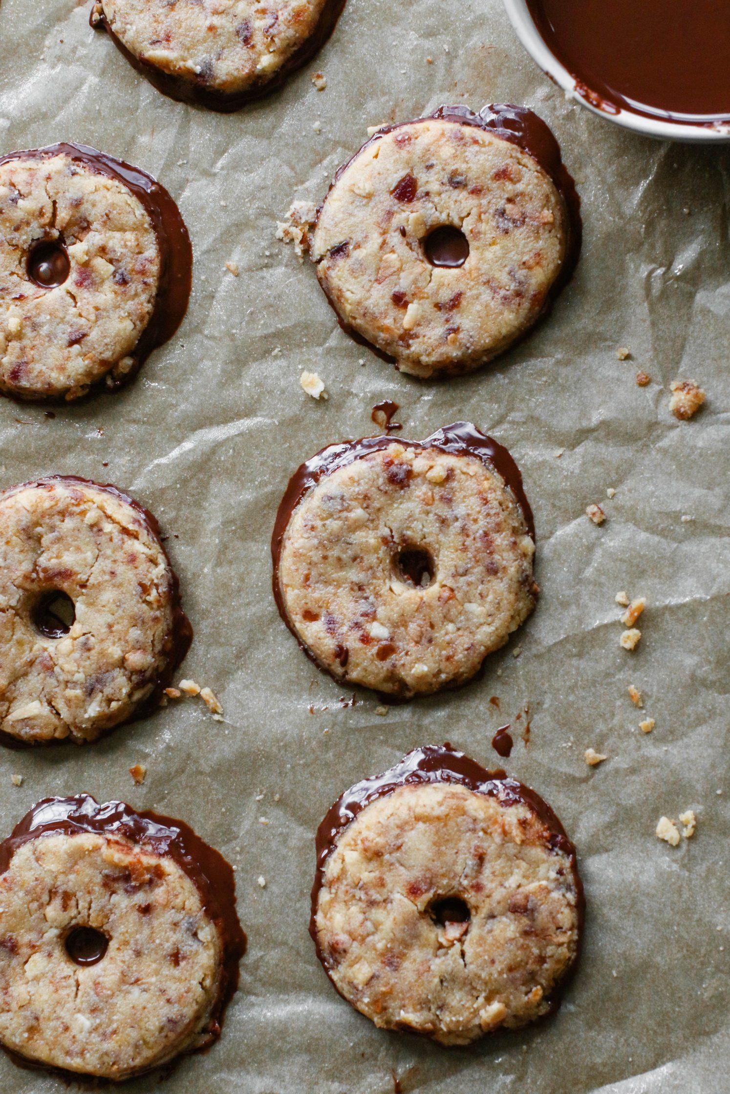 Vegan Toasted Coconut Samoas dipped in melted chocolate on parchment paper