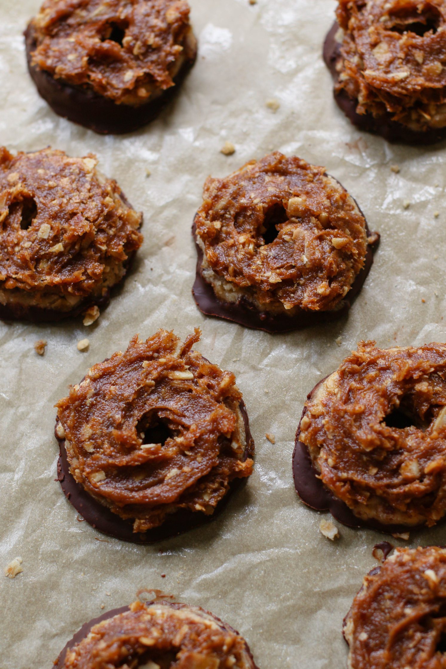 Vegan Toasted Coconut Samoas on parchment lined baking sheet with layer of date caramel on top