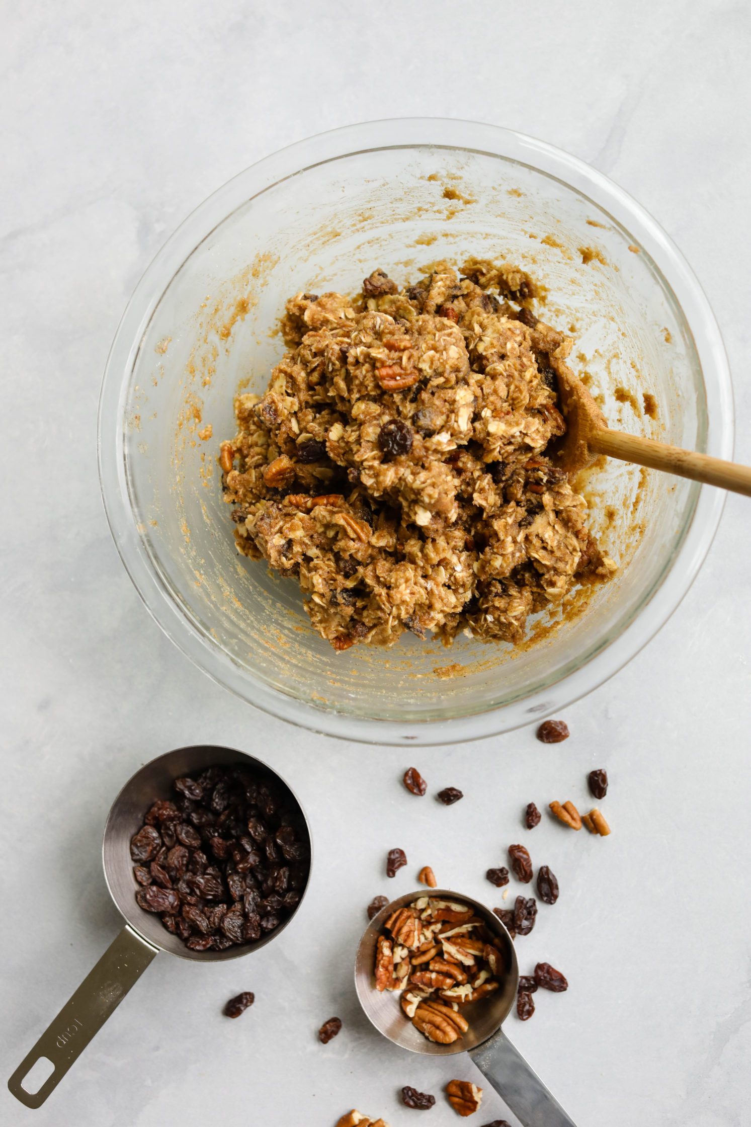 Oatmeal Raisin Pecan Cookies Batter in mixing bowl with wooden spoon by Flora & Vino