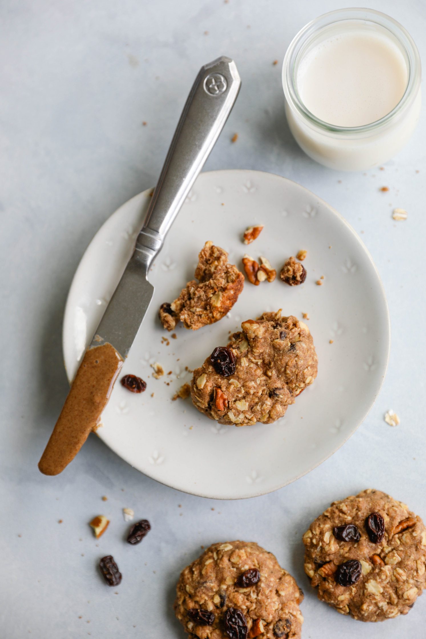 Oatmeal Raisin Pecan Cookies in pieces on plates with almond milk by Flora & Vino