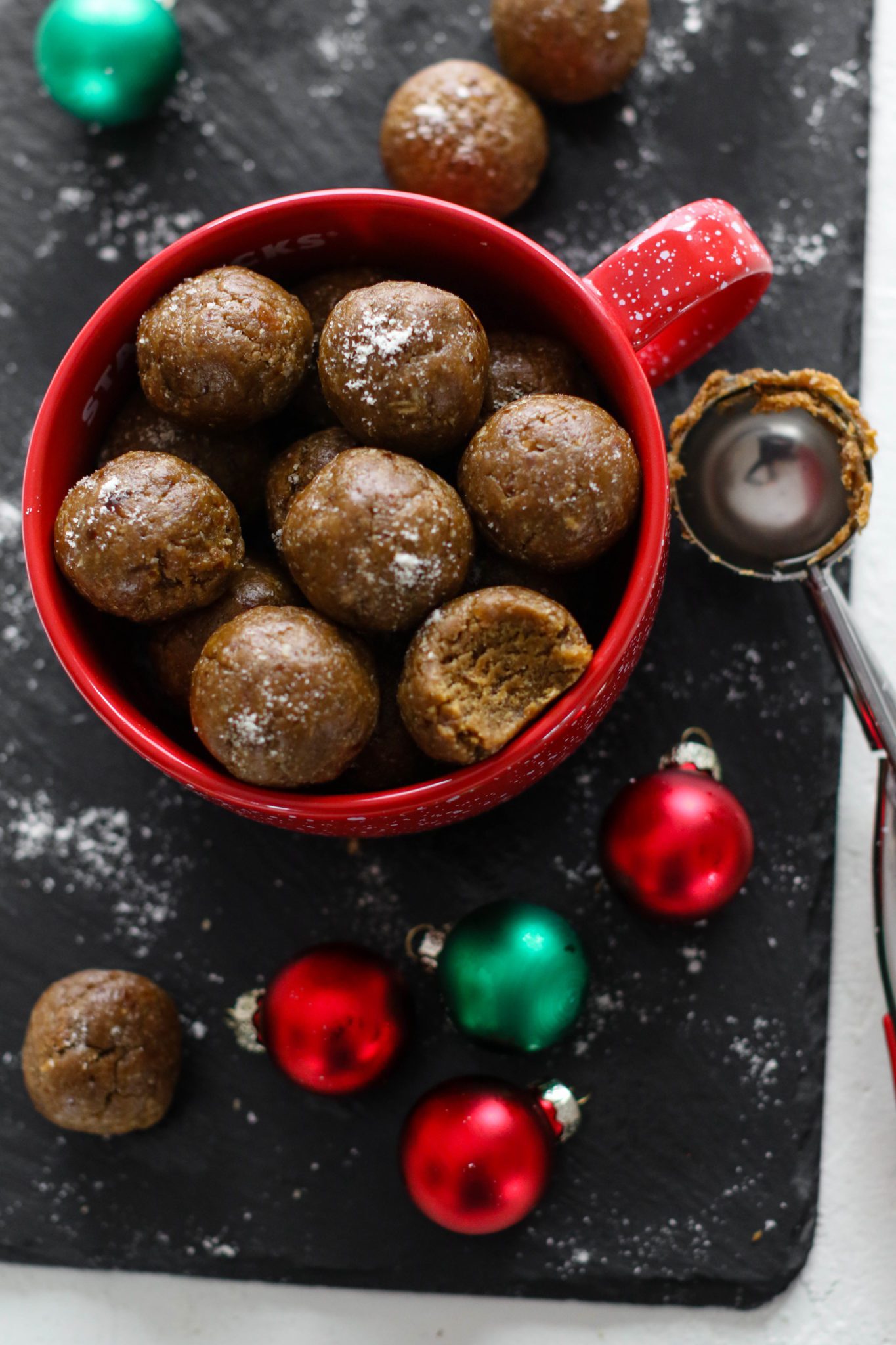 Gingerbread Bliss Balls in red mug with bite out of one by Flora & Vino