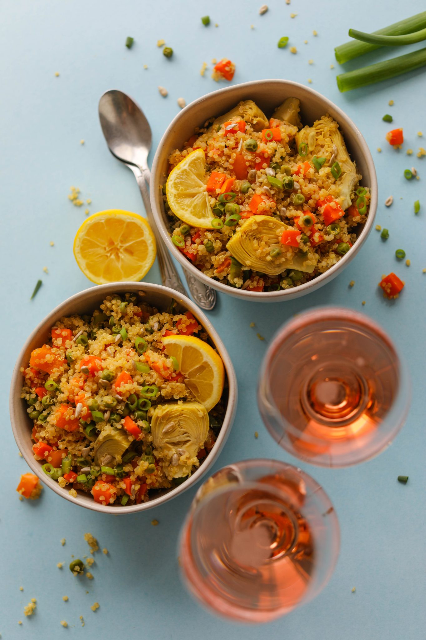 Spring Quinoa Primavera served in bowls on blue paper with spoons and glass of Rosé