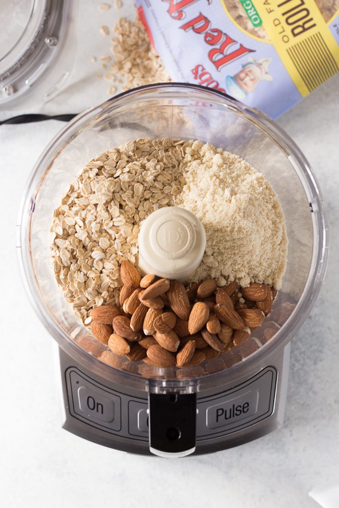 almonds, oats, and protein powder in blender by Flora & Vino