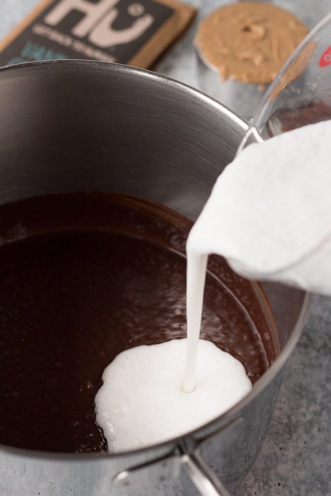 adding milk to melted chocolate in pot