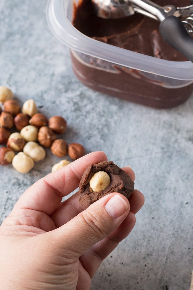 hand adding hazelnut to center of Vegan Ferrero Rocher Truffles