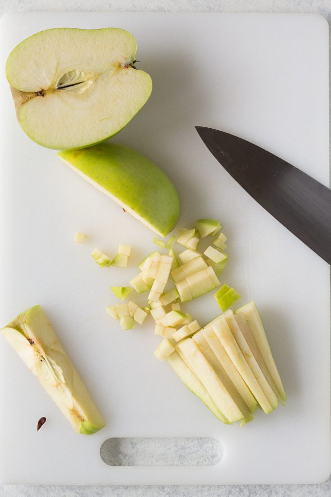 green apples diced on cutting board with knife by Flora & Vino