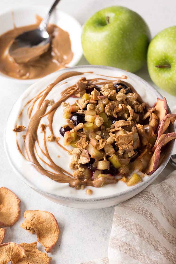 Apple Pie Yogurt Bowl with almond butter drizzled on top by Flora & Vino 