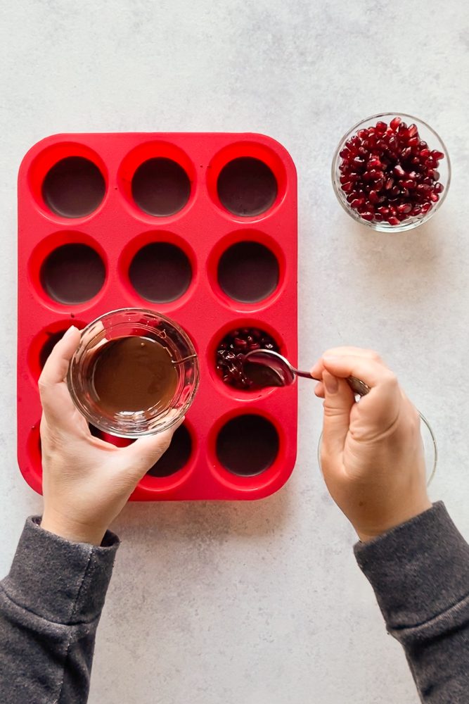 drizzling melted chocolate on top of chocolate pomegranate cups by Flora & Vino