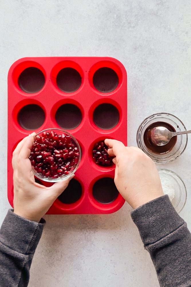 adding pomegrate seeds to chocolate in silicone muffin mold by Flora & Vino