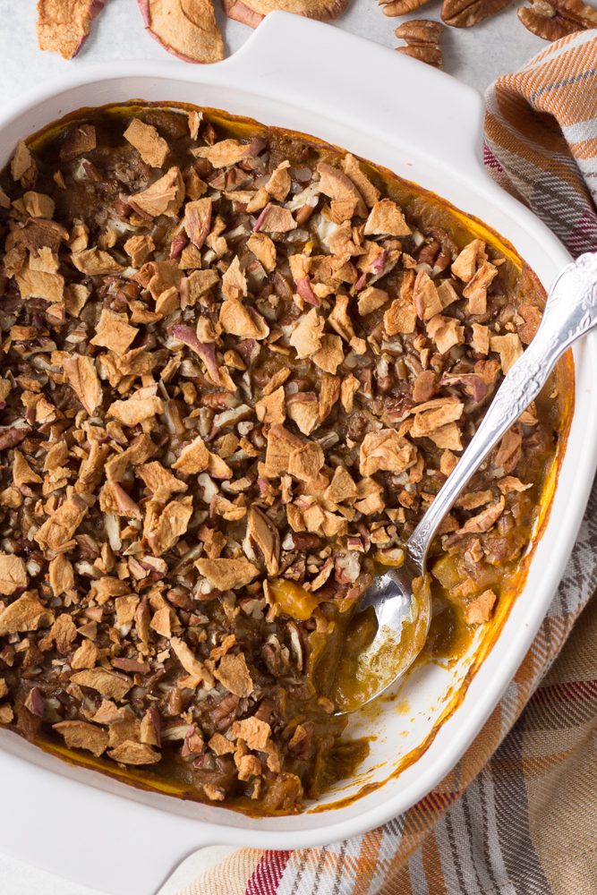 Pumpkin Apple Bake served in casserole dish with metal spoon topped with apple chips
