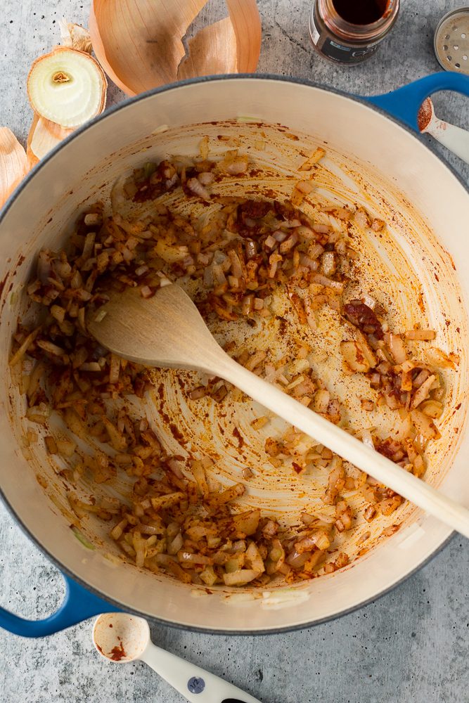 onions and tomato paste sautéed in pot with wooden spoon by Flora & Vinio
