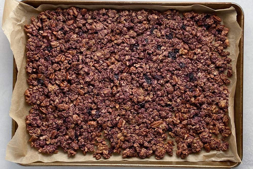 Triple Berry Granola baked on parchment lined baking sheet