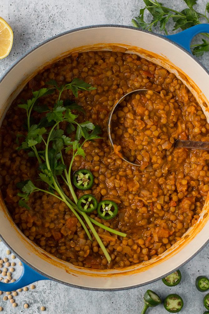 Lentil Tomato Soup served in a pot with a ladle by Flora & Vino