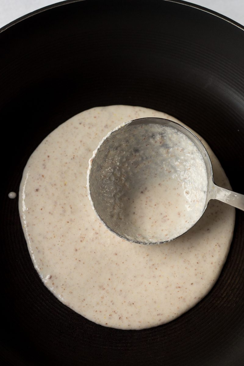 ladle pouring grain free flatbread mix into skillet