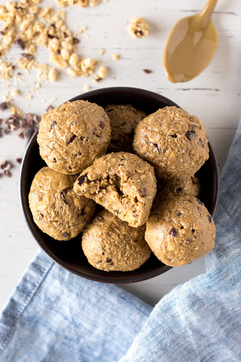 Everything Granola Bites served in bowl with bite out of one with spoon of SunButter in the corner and granola scattered with blue towel