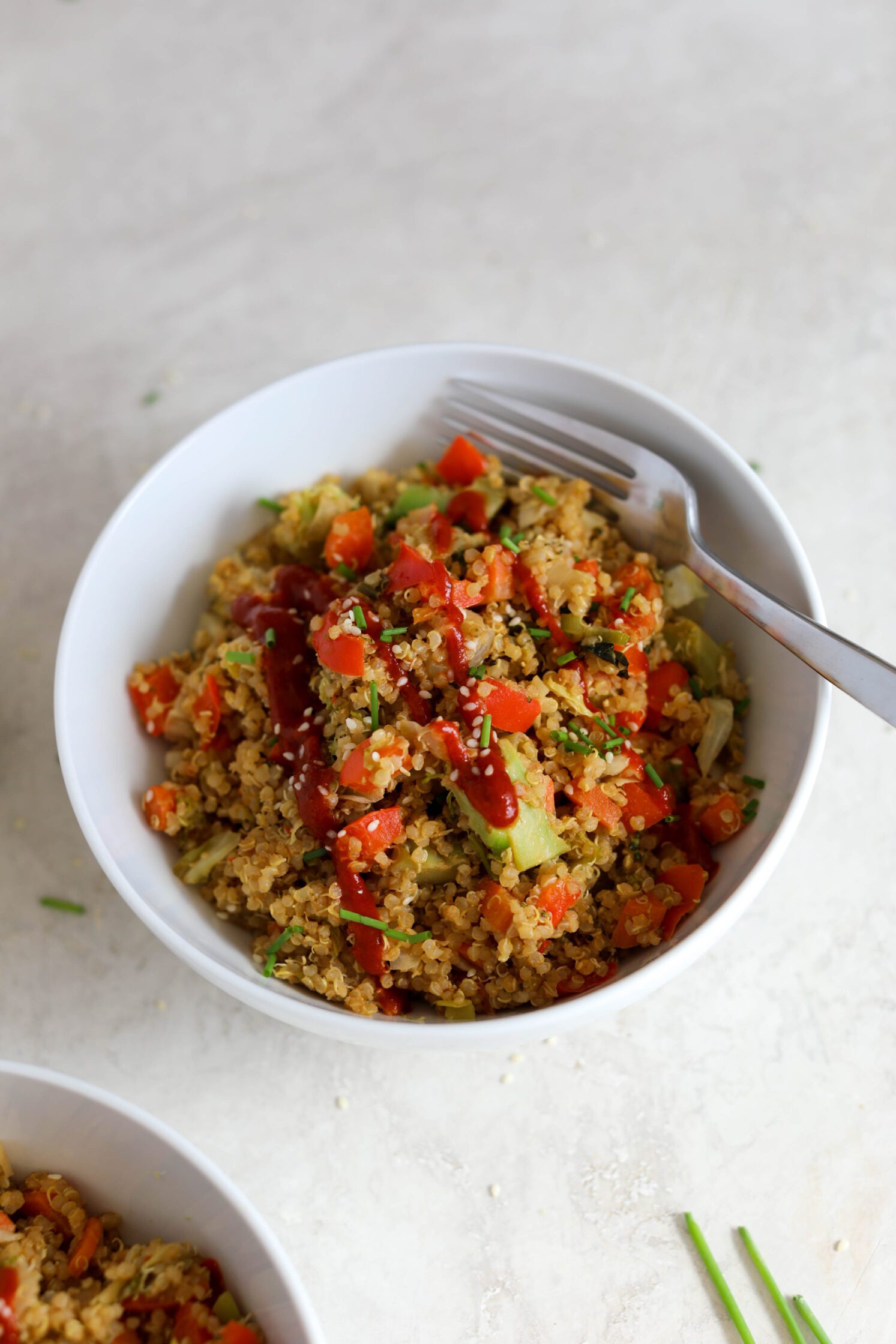 SunButter Quinoa Fried Rice served in a bowl with sriracha, chives, and sesame seeds by Flora & Vino