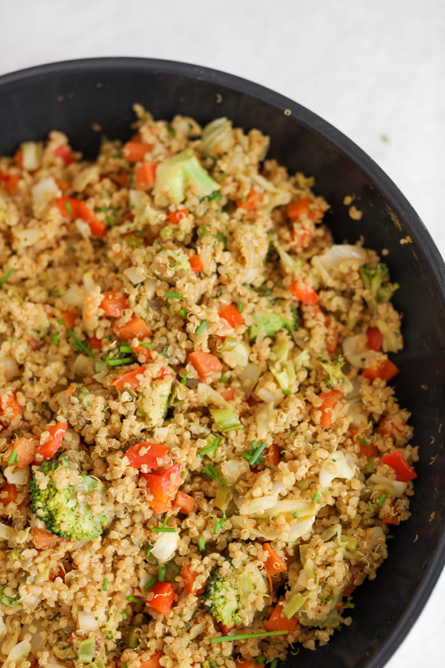 SunButter Quinoa Fried Rice in cast iron skillet with chives on top by Flora & Vino