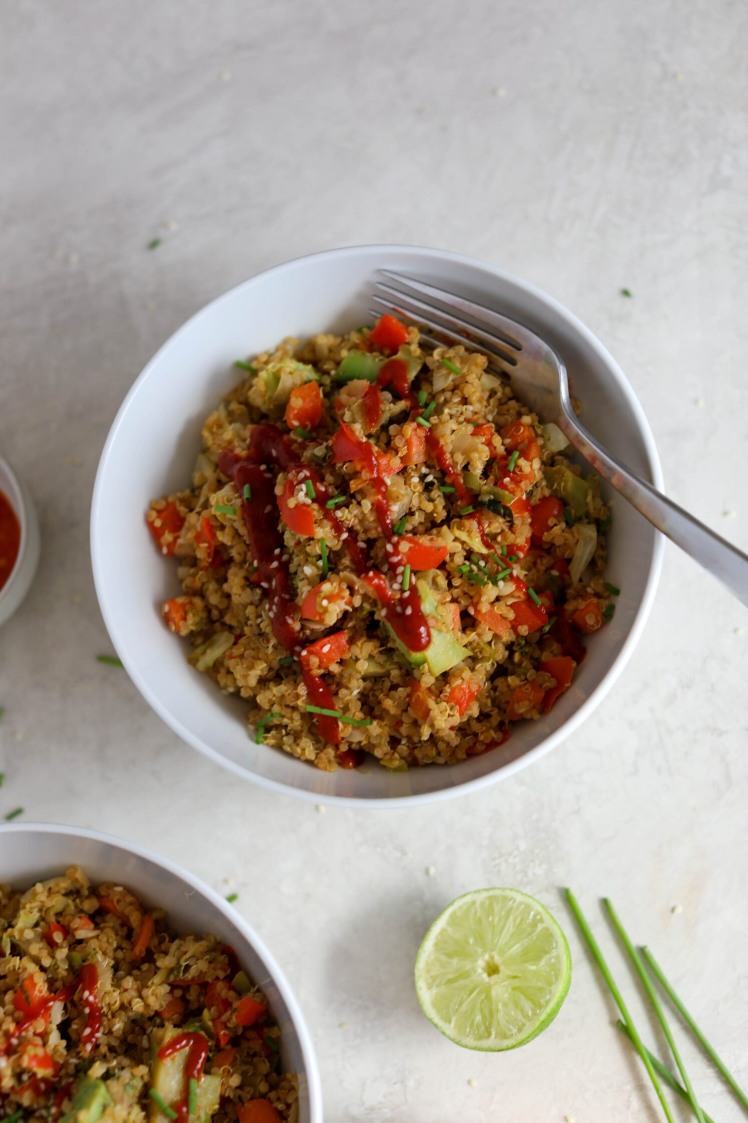 SunButter Quinoa Fried Rice served in a bowl with sriracha and a fork by Flora & Vino
