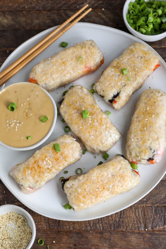 Crispy Rice Paper Dumplings served on plate topped with green onions and sesame seeds with sauce and chopsticks
