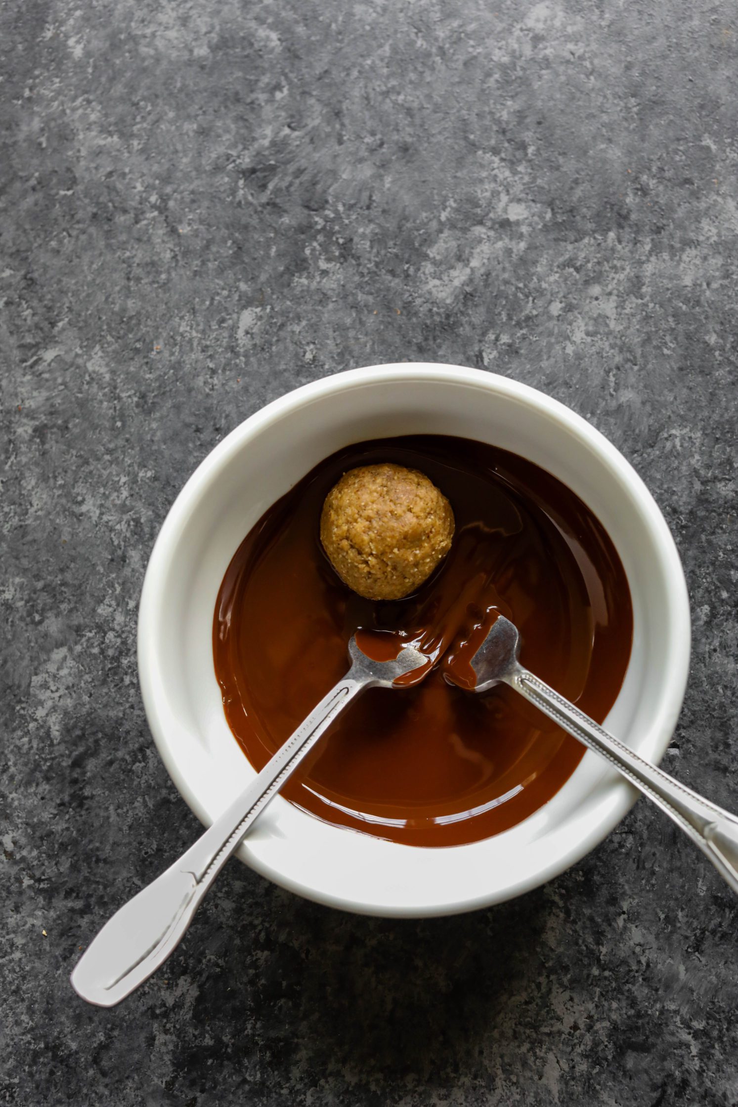truffles dipped in melted chocolate in bowl with two forks