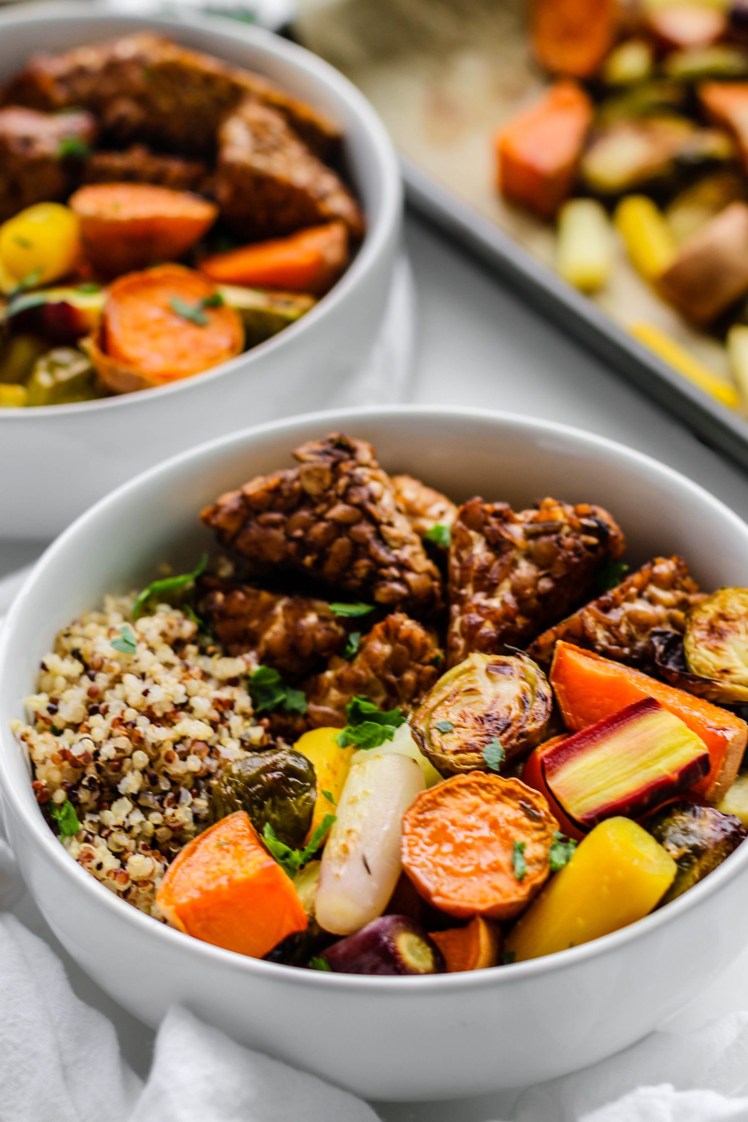 Maple Balsamic Tempeh Bowls served in bowls with rainbow veggies and sheet pan on side